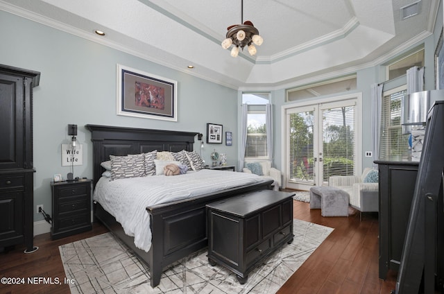 bedroom with light wood-type flooring, a tray ceiling, multiple windows, and crown molding