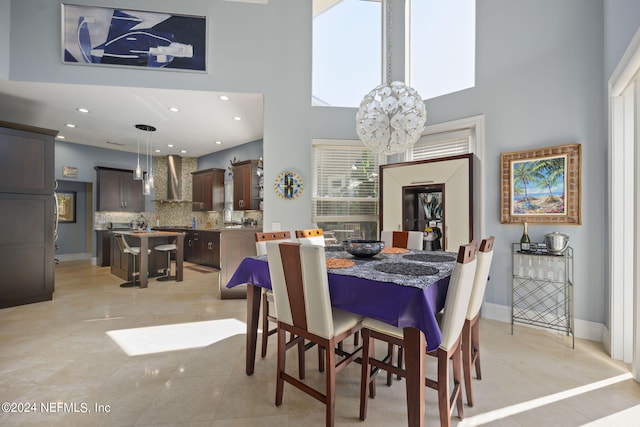 dining room featuring a towering ceiling, a notable chandelier, plenty of natural light, and light tile patterned floors