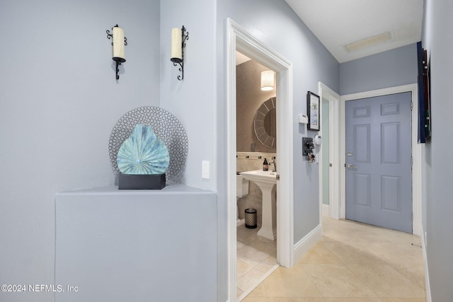 hall featuring sink and light tile patterned floors