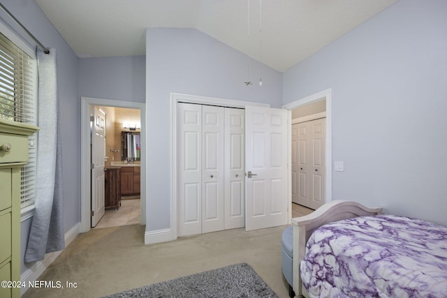 bedroom featuring light carpet, a closet, ensuite bath, and high vaulted ceiling