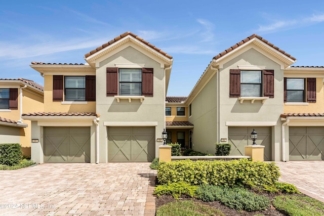 mediterranean / spanish-style house featuring decorative driveway, an attached garage, and stucco siding