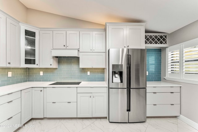 kitchen featuring lofted ceiling, white cabinets, tasteful backsplash, and stainless steel fridge