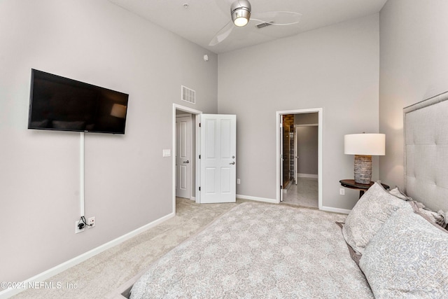 bedroom with a towering ceiling, light carpet, connected bathroom, and ceiling fan