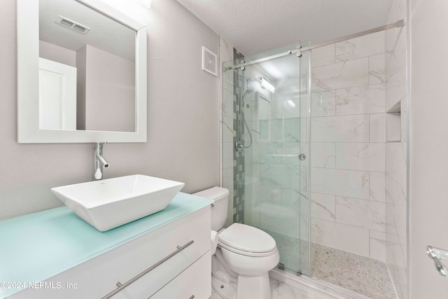 bathroom featuring a textured ceiling, a shower with door, vanity, and toilet