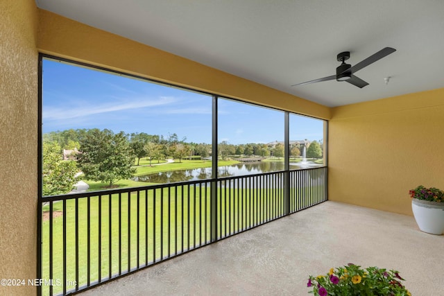 unfurnished sunroom featuring a ceiling fan and a water view