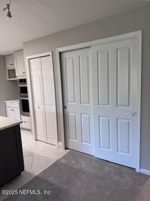 unfurnished bedroom featuring baseboards, marble finish floor, and two closets