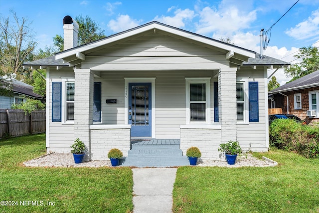 bungalow-style house featuring covered porch and a front yard