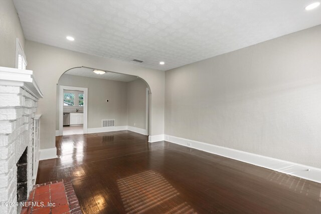 unfurnished living room with a stone fireplace and hardwood / wood-style floors