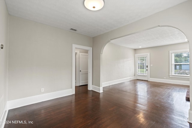 empty room with dark hardwood / wood-style flooring and a textured ceiling