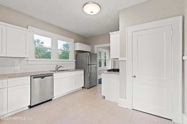 kitchen featuring white cabinets, backsplash, stainless steel appliances, and sink