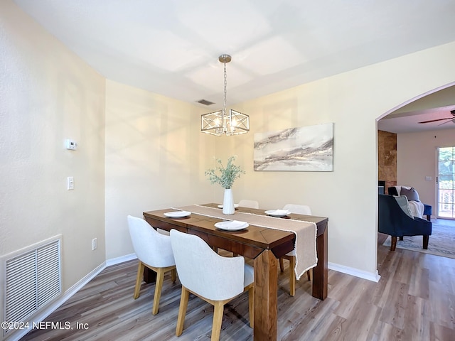 dining area featuring ceiling fan with notable chandelier and hardwood / wood-style flooring