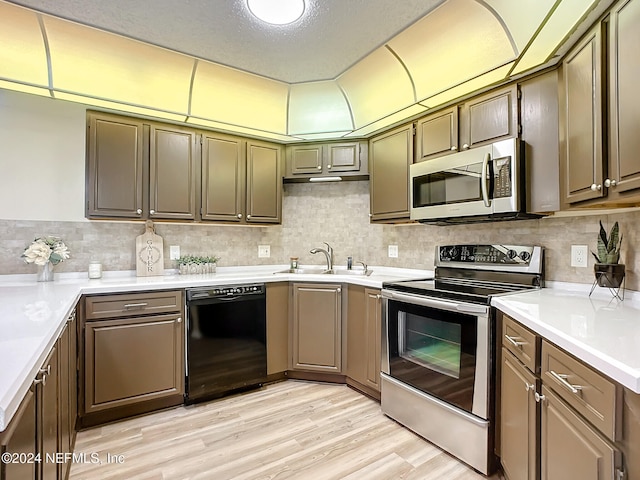 kitchen with a textured ceiling, light hardwood / wood-style floors, sink, and stainless steel appliances