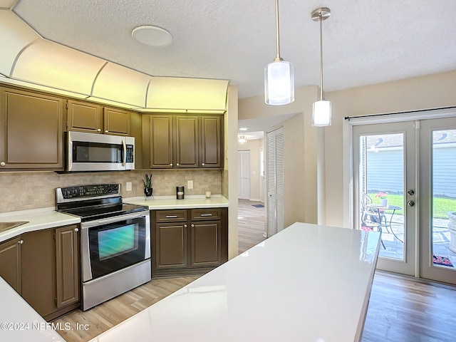 kitchen with french doors, decorative backsplash, decorative light fixtures, dark brown cabinets, and stainless steel appliances