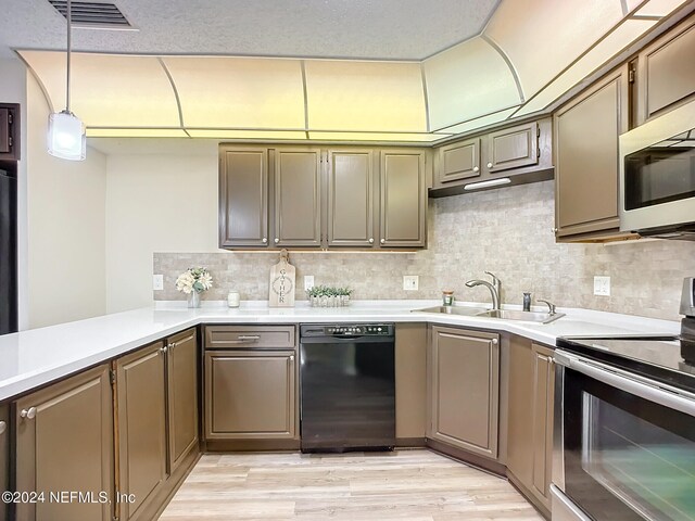 kitchen with electric stove, sink, hanging light fixtures, black dishwasher, and light hardwood / wood-style floors