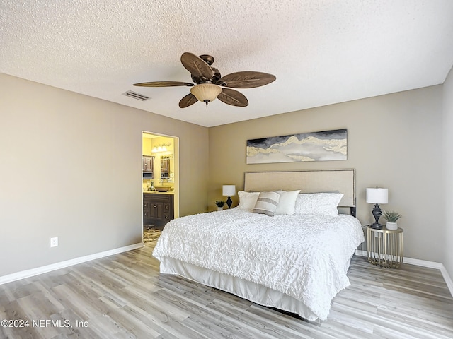 bedroom with connected bathroom, ceiling fan, a textured ceiling, and light wood-type flooring