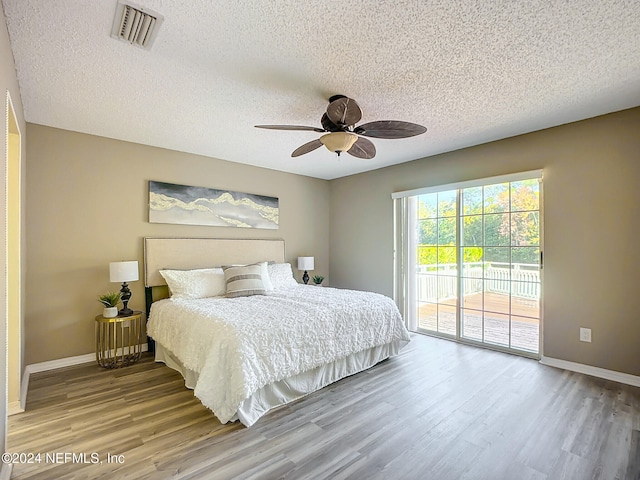 bedroom featuring a textured ceiling, access to outside, ceiling fan, and hardwood / wood-style flooring