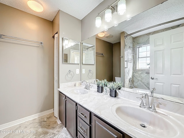 bathroom featuring tiled shower, vanity, a textured ceiling, and toilet