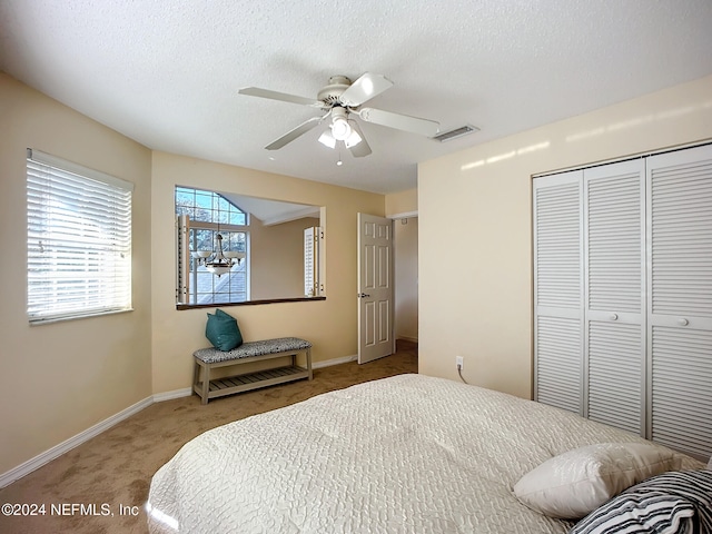 carpeted bedroom with ceiling fan, a closet, and a textured ceiling