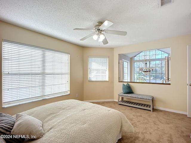 bedroom featuring a textured ceiling, ceiling fan, and light carpet