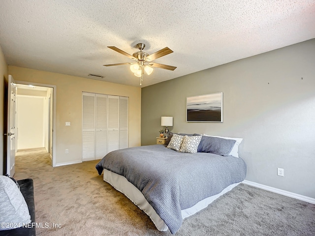 carpeted bedroom featuring a textured ceiling, a closet, and ceiling fan