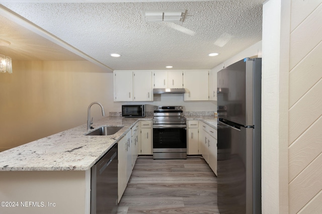 kitchen with kitchen peninsula, white cabinets, light hardwood / wood-style flooring, sink, and stainless steel appliances