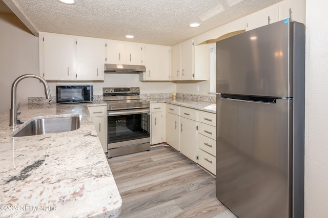 kitchen featuring appliances with stainless steel finishes, a textured ceiling, sink, and light wood-type flooring