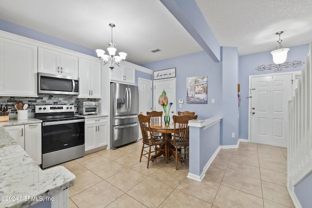 kitchen with hanging light fixtures, decorative backsplash, white cabinetry, light stone countertops, and stainless steel appliances