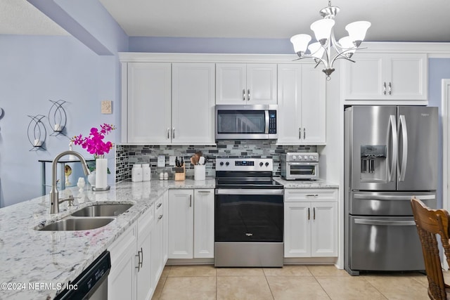 kitchen featuring decorative backsplash, white cabinets, stainless steel appliances, decorative light fixtures, and sink