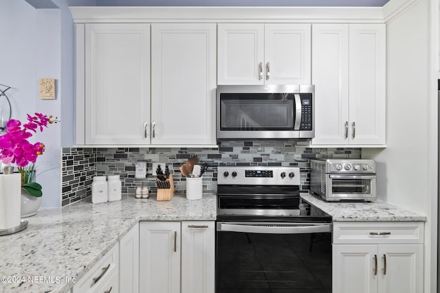 kitchen with white cabinets, stainless steel appliances, light stone countertops, and decorative backsplash