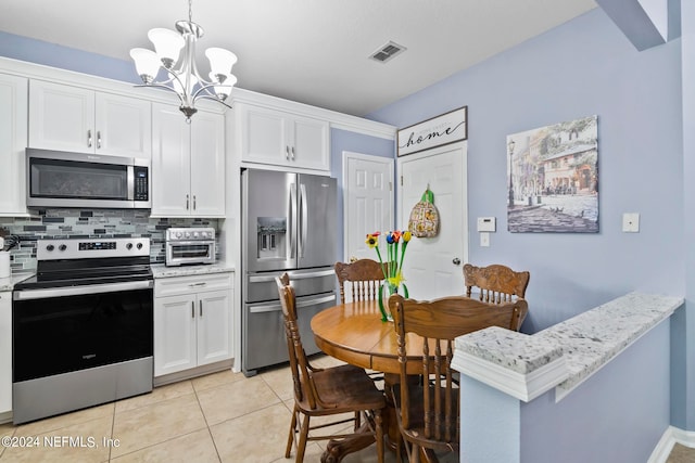 kitchen with decorative backsplash, white cabinets, light tile patterned floors, stainless steel appliances, and decorative light fixtures