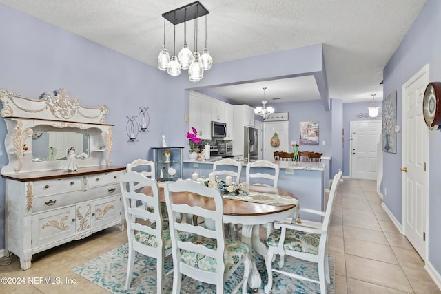 dining area with a textured ceiling, light tile patterned flooring, and an inviting chandelier