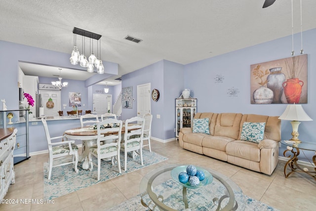 living room with a chandelier, a textured ceiling, and light tile patterned floors