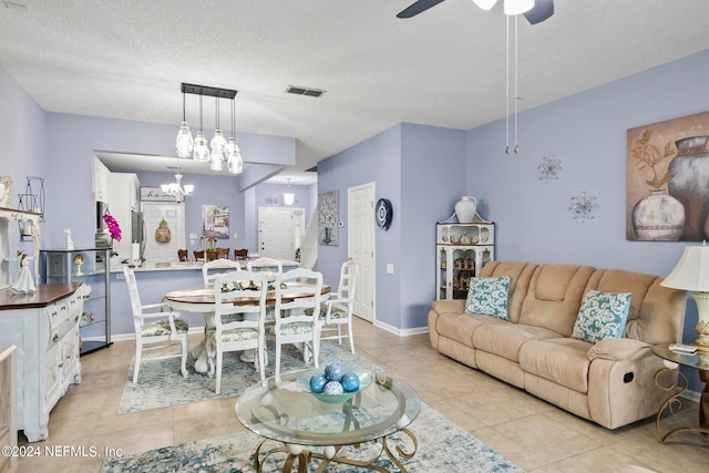 tiled living room featuring ceiling fan with notable chandelier and a textured ceiling