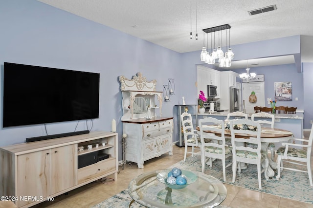 tiled dining area with a textured ceiling and a chandelier