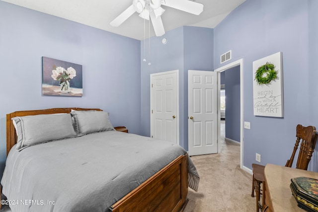 bedroom featuring a towering ceiling, ceiling fan, and light colored carpet