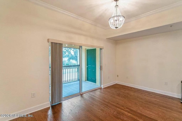 spare room with ornamental molding, dark wood-type flooring, and a notable chandelier