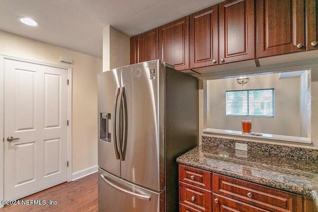 kitchen featuring stainless steel fridge, dark stone countertops, and light hardwood / wood-style flooring