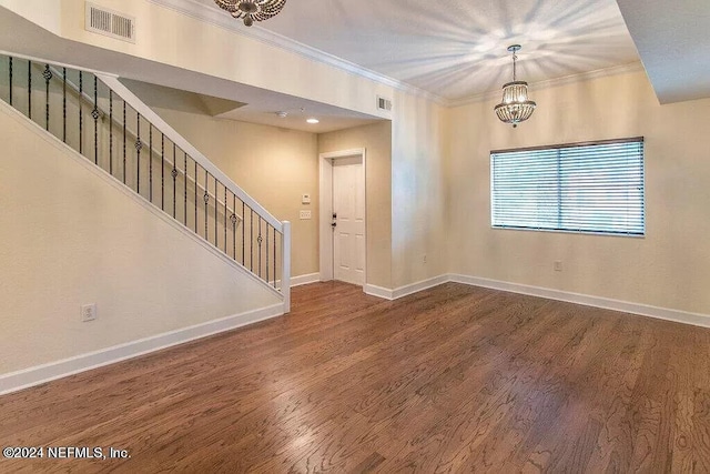 spare room featuring wood-type flooring, crown molding, and an inviting chandelier