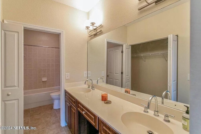 full bathroom featuring vanity, tile patterned floors, toilet, and tiled shower / bath combo