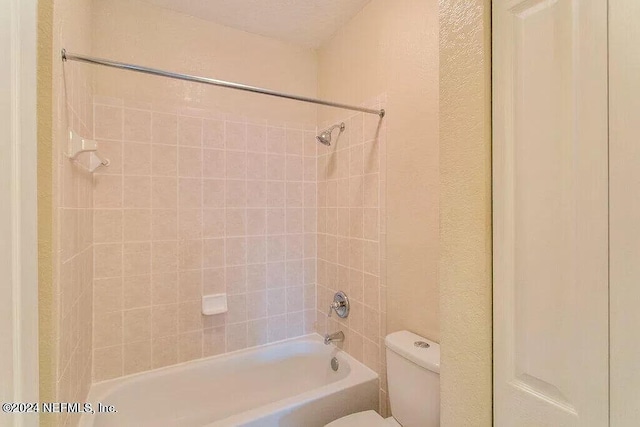 bathroom featuring toilet and tiled shower / bath