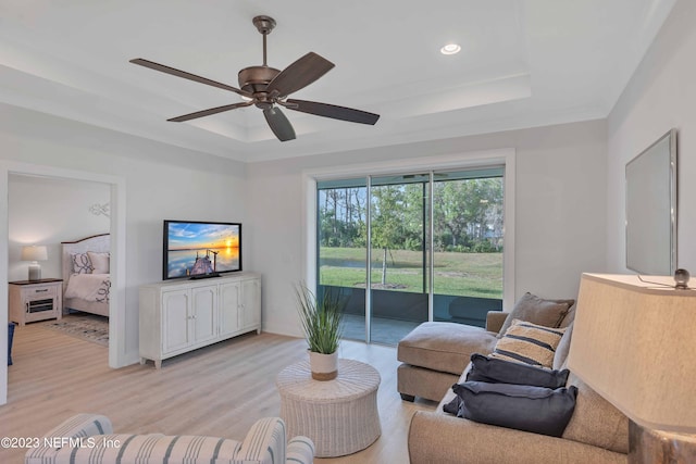 living room with ceiling fan, a raised ceiling, and light hardwood / wood-style flooring