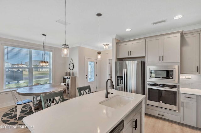 kitchen with gray cabinetry, sink, stainless steel appliances, light hardwood / wood-style flooring, and pendant lighting