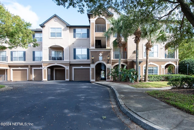 10961 Burnt Mill Rd Unit 421, Jacksonville, FL 32256 - view of property featuring a garage, driveway, and stucco siding