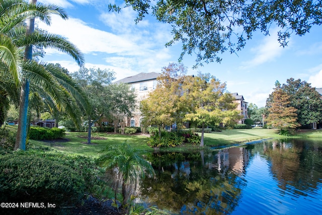 view of home's community with a water view and a lawn