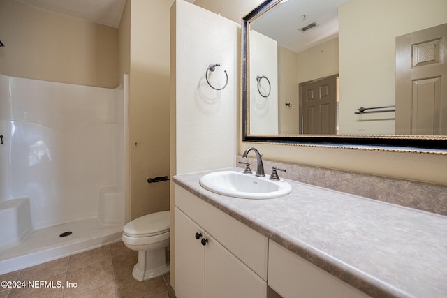 bathroom with tile patterned flooring, vanity, a shower, and toilet