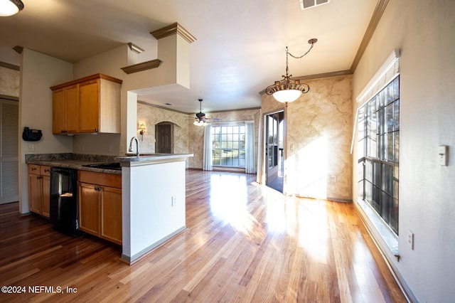 kitchen with black dishwasher, sink, hanging light fixtures, ornamental molding, and hardwood / wood-style flooring