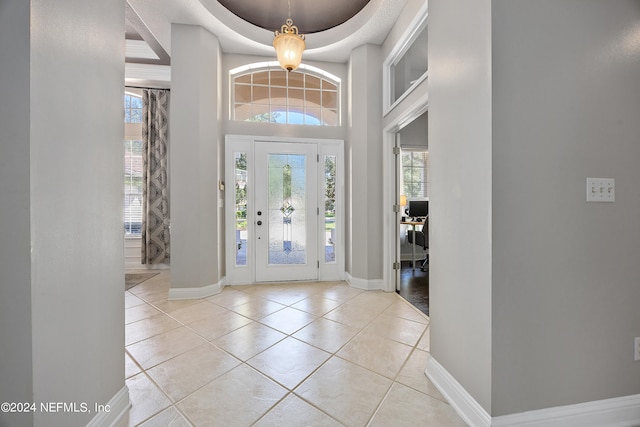 tiled foyer featuring a tray ceiling and a towering ceiling