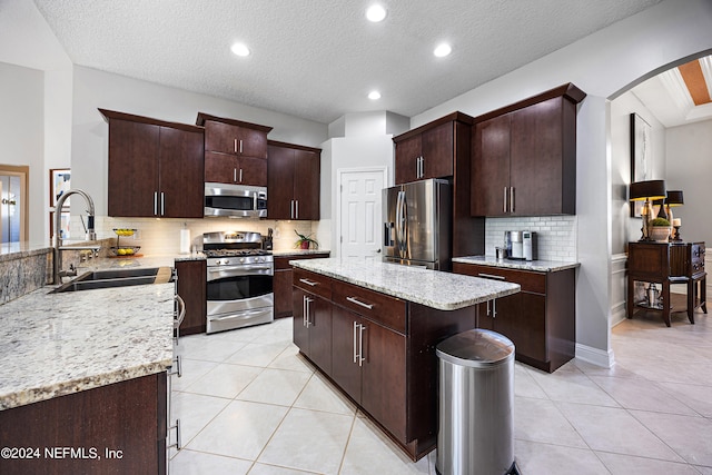 kitchen with sink, dark brown cabinets, stainless steel appliances, and light tile patterned flooring