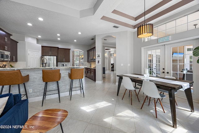 kitchen featuring stainless steel appliances, dark brown cabinets, decorative light fixtures, and french doors