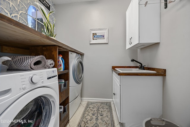 washroom with sink, light tile patterned floors, cabinets, and washing machine and clothes dryer